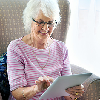 Image of a mature lady viewing her tablet VDU with her reading glasses on